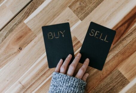 Coinbase - a person holding two small black books with the words buy and sell on them