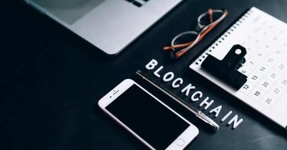 Blockchain - Smartphone, Pen, Calendar and Eyeglasses on Flat Surface