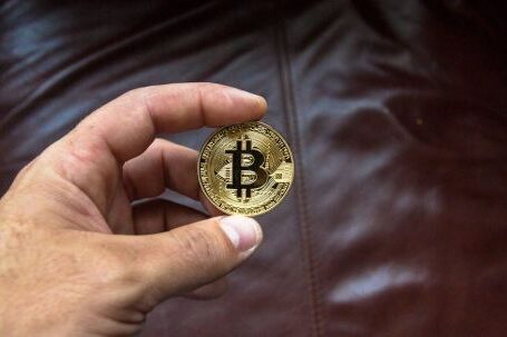 Blockchain - Round Gold-colored and Black Coin on Person's Hand