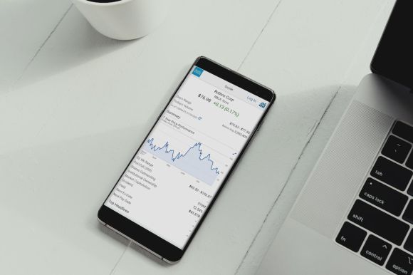 Coinbase - a cell phone sitting on top of a table next to a laptop