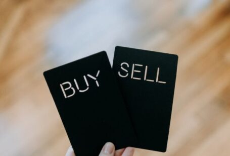 Coinbase - a hand holding two black cards with the words buy and sell written on them