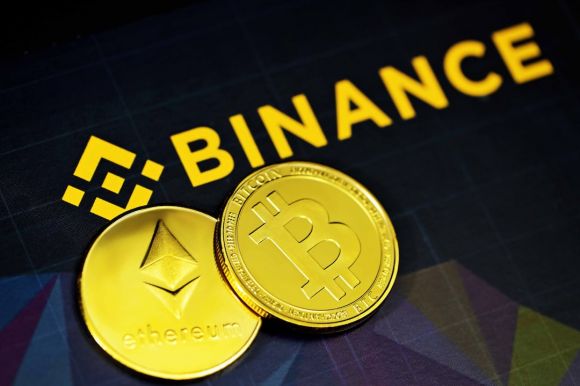 Binance - two gold bitcoins sitting next to a binance sign