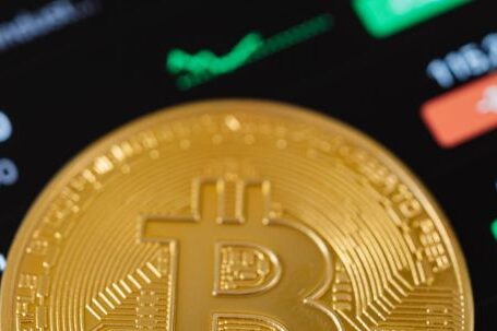 Stock Crypto - Gold Bitcoin Coin Lying on a Phone Displaying Cryptocurrency Graphs