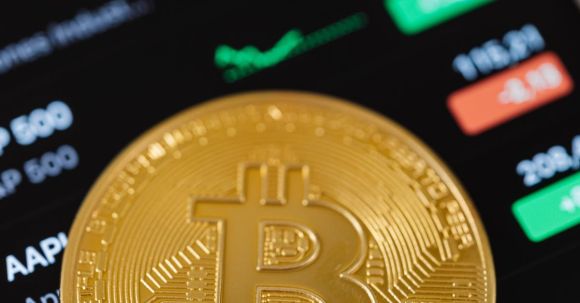 Stock Crypto - Gold Bitcoin Coin Lying on a Phone Displaying Cryptocurrency Graphs